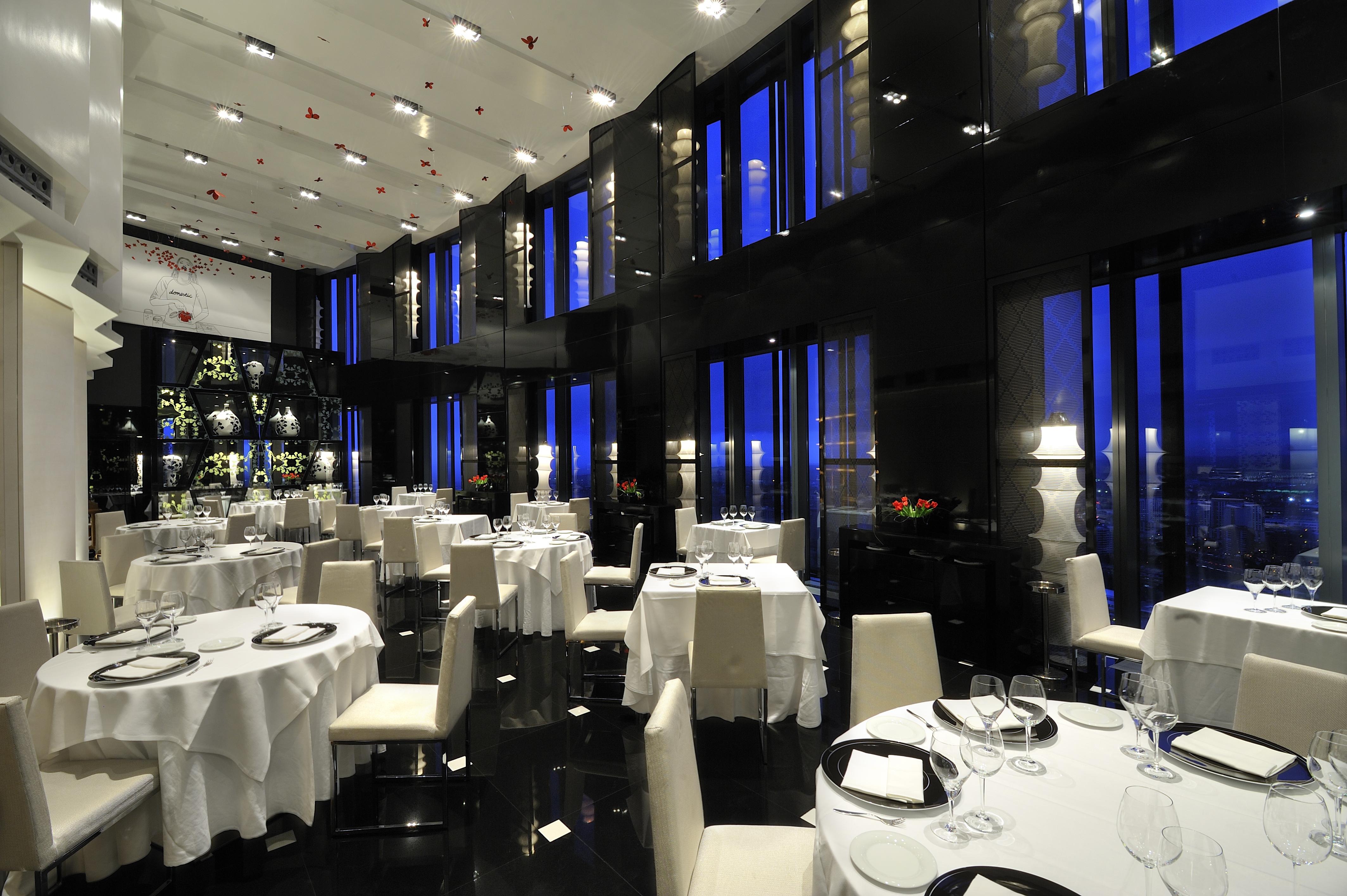 Eurostars Madrid Tower Hotell Exteriör bild The photo shows an elegant restaurant interior, characterized by its modern design and luxurious ambiance. The space features several round dining tables, each set with white tablecloths and tableware, including wine glasses. The walls are made of da