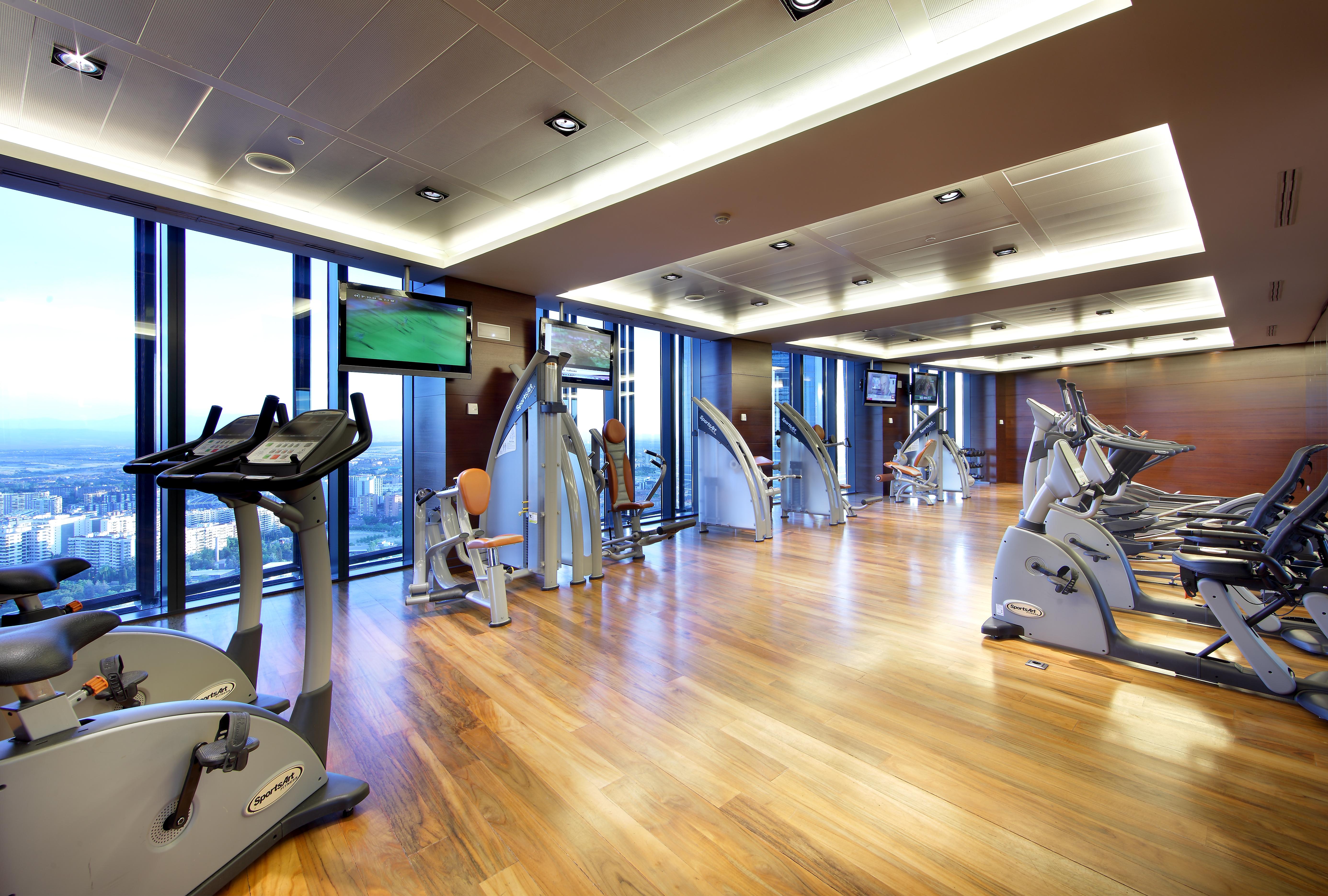 Eurostars Madrid Tower Hotell Exteriör bild The photo shows a modern gym or fitness center. It features large windows that let in natural light, providing a view of the outside. The flooring is made of polished wood, giving the space a warm and inviting atmosphere. Various exercise machines ar