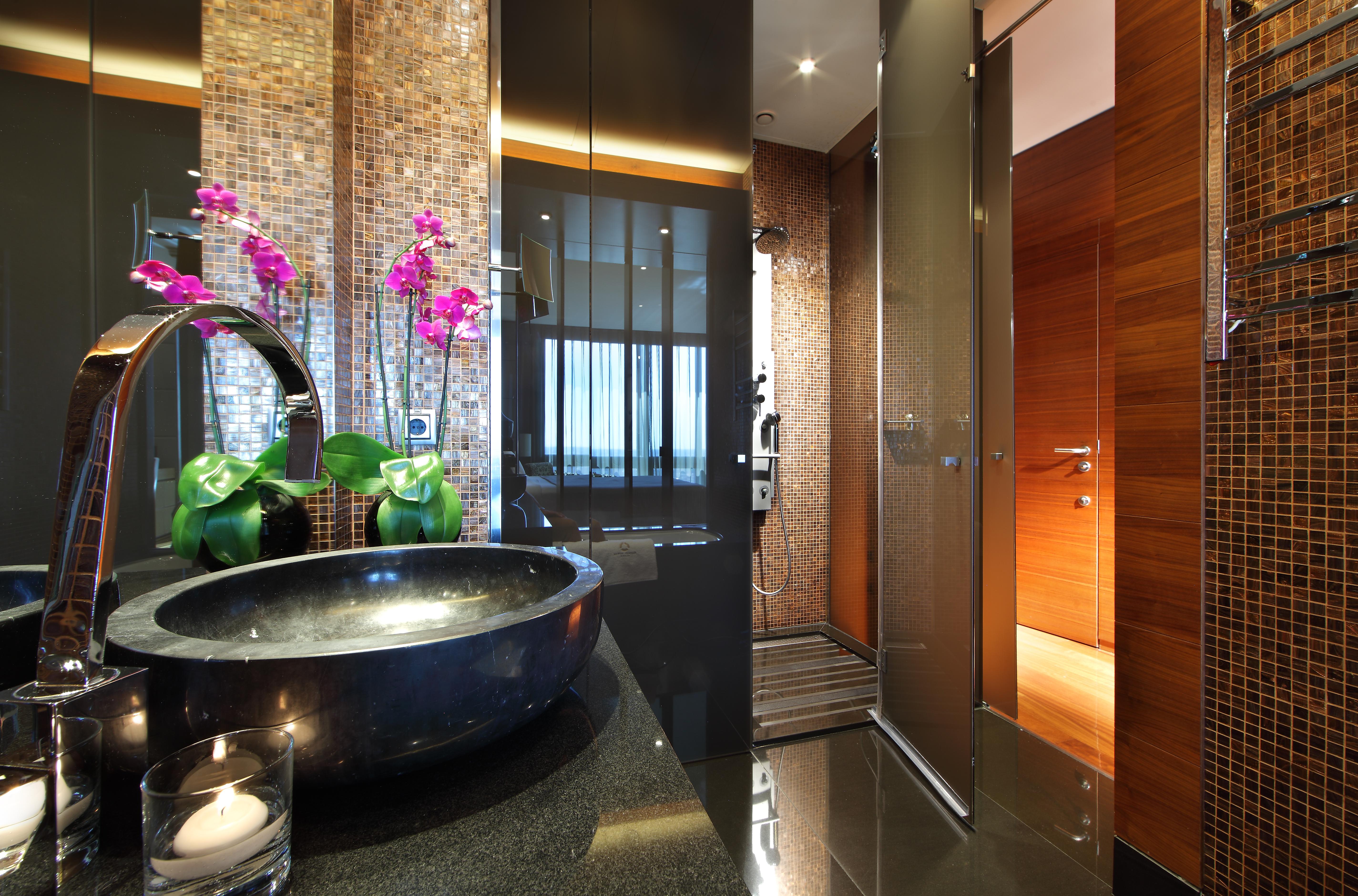 Eurostars Madrid Tower Hotell Exteriör bild The photo shows a modern and stylish bathroom. On the left, there is a sleek black basin set on a dark countertop, adorned with decorative elements such as a candle and potted green plants. To the side, there are elegant pink orchids adding a pop of 