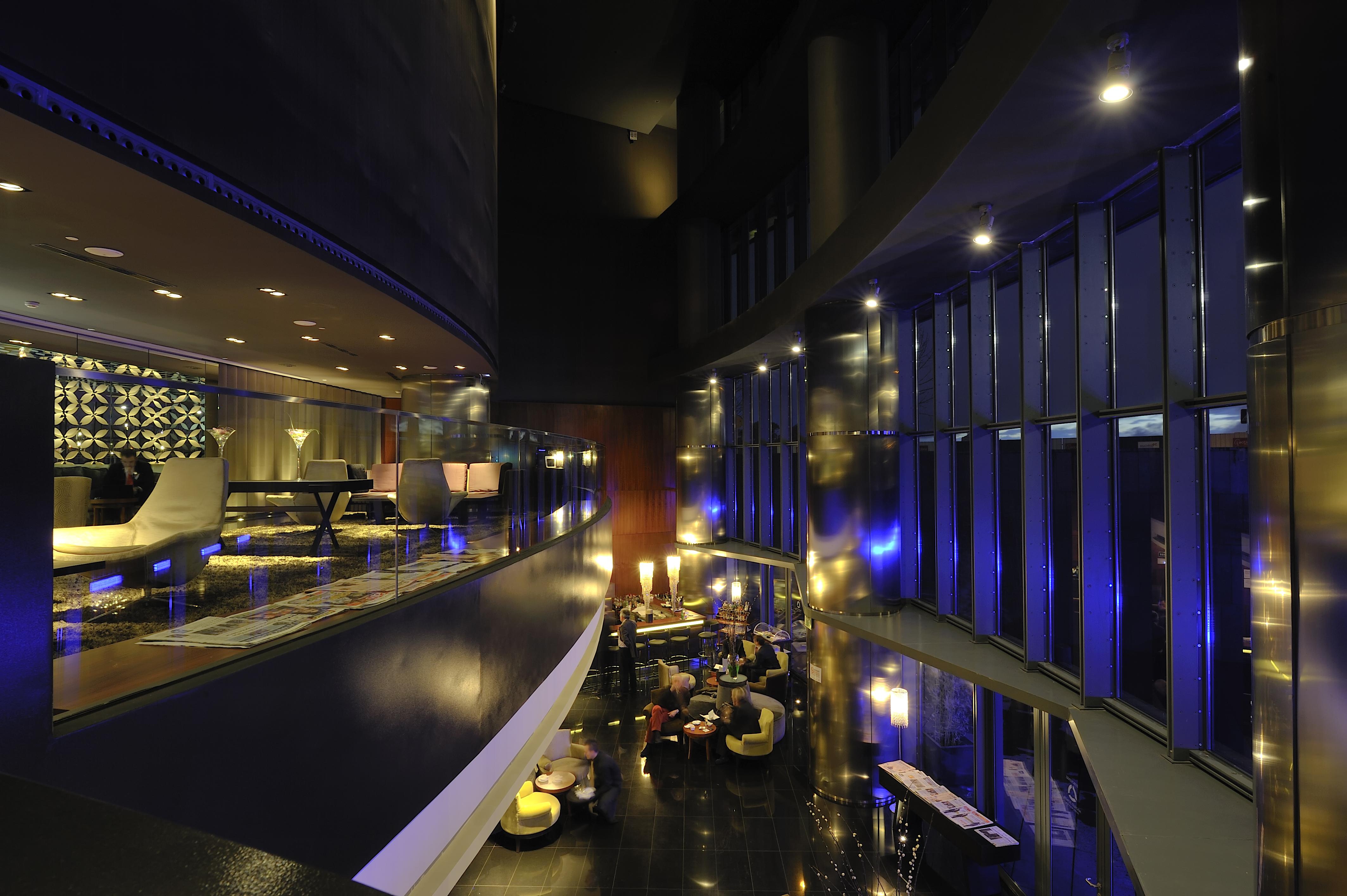 Eurostars Madrid Tower Hotell Exteriör bild The photo depicts a modern and stylish interior space, likely a hotel lobby or lounge area. The design features smooth lines and a sleek aesthetic with a predominantly dark color palette complemented by subtle lighting. 

To the left, there are plush