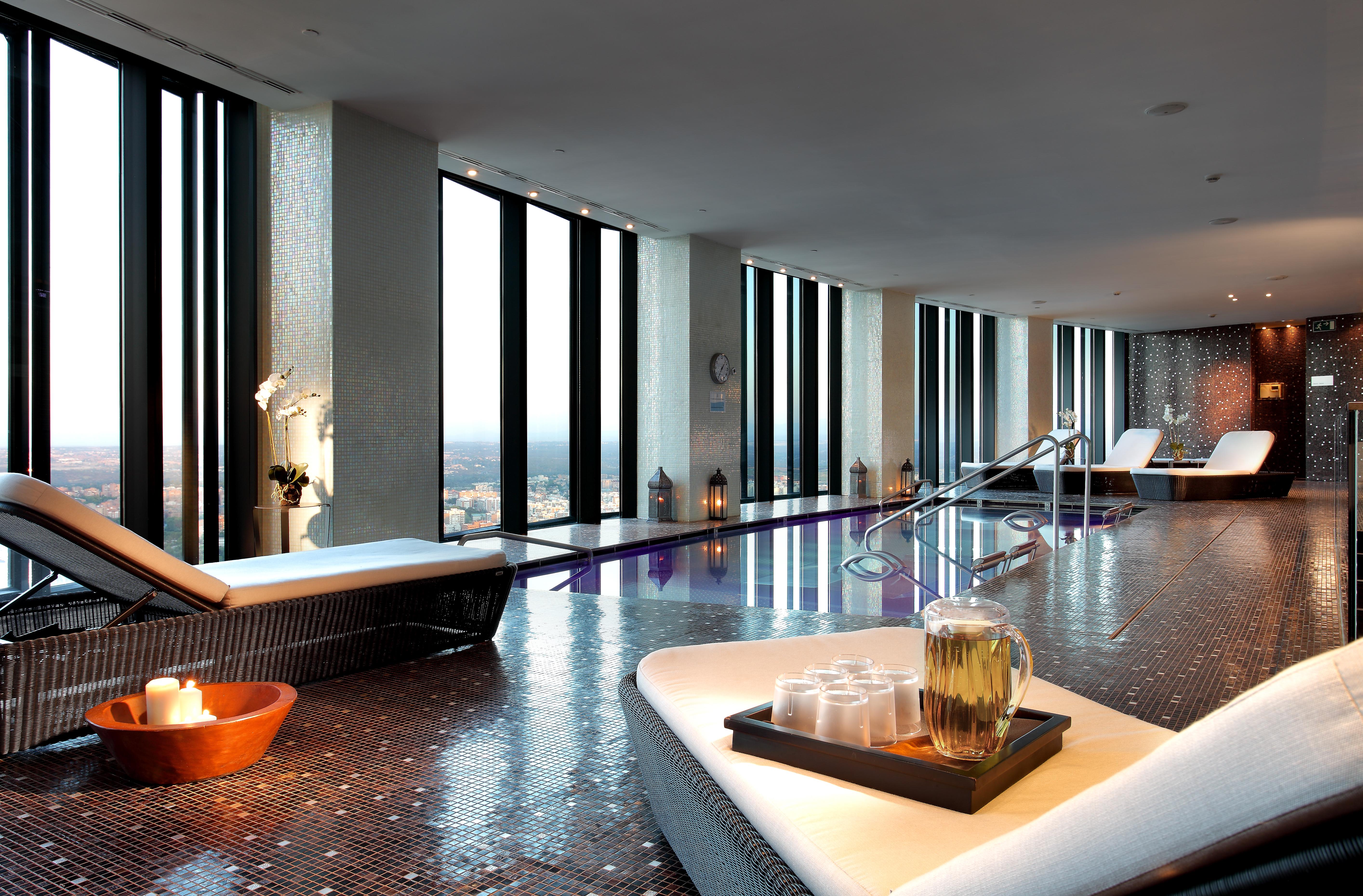 Eurostars Madrid Tower Hotell Exteriör bild The photo depicts a luxurious spa interior with large windows that offer a panoramic view of the outside. The space features sleek, modern lounge chairs and a tranquil atmosphere. There is a pool area, and the floor is tiled with reflective materials