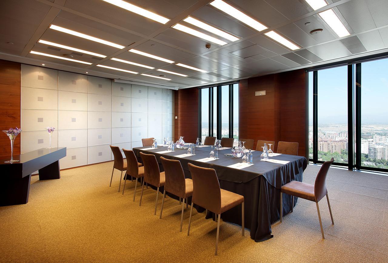 Eurostars Madrid Tower Hotell Exteriör bild The photo shows a modern conference room with a long table set up for meetings. There are several chairs around the table, and the table is covered with a dark tablecloth. On the table, there are glass pitchers and cups, indicating it is prepared for