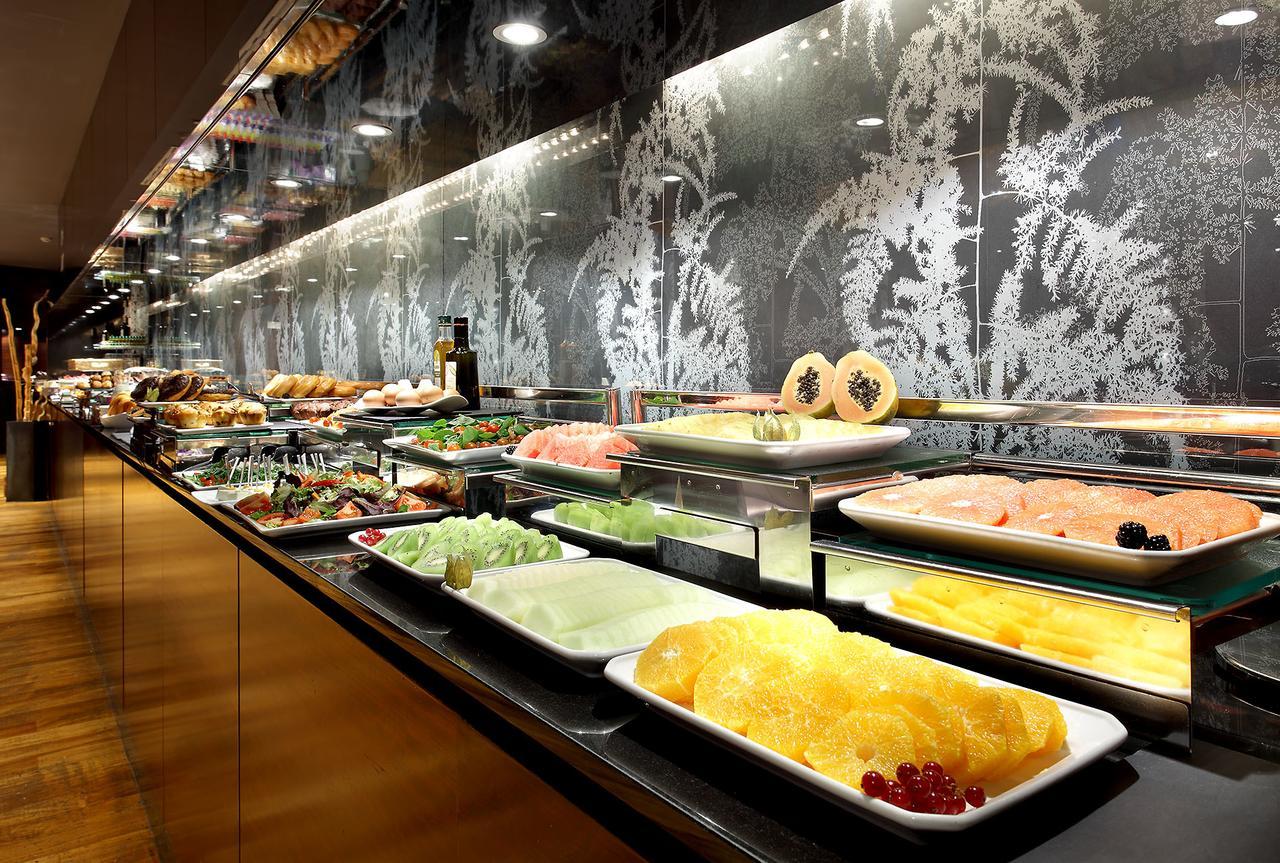 Eurostars Madrid Tower Hotell Exteriör bild The photo shows a buffet display featuring a variety of dishes and ingredients. There are plates filled with different types of food, including seafood, fruits, and vegetables. The arrangement is visually appealing, with the food presented on glass s