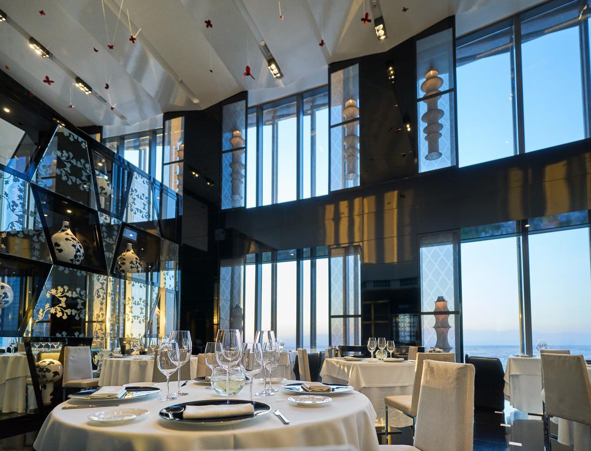 Eurostars Madrid Tower Hotell Exteriör bild The photo shows an elegant restaurant interior featuring a modern design. The space has large windows that provide a view of the outside, allowing natural light to fill the room. The decor includes artistic elements, such as sculptures and decorative