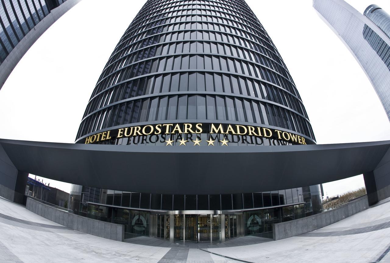 Eurostars Madrid Tower Hotell Exteriör bild The photo shows a tall, modern glass building that serves as the Eurostars Madrid Tower Hotel. The building features a sleek, curved design with a prominent entrance. Above the entrance, the hotel's name is displayed in large golden letters, indicati