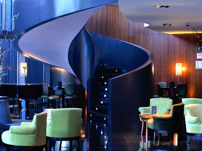 Eurostars Madrid Tower Hotell Exteriör bild The photo depicts a stylish and modern interior, likely of a bar or lounge. The focal point is a unique spiral staircase that has a sleek, flowing design, leading to another level. The surrounding area features a combination of dark wood panels and g